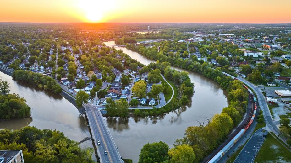 Image of Aerial horseshoe riverbend train and small cityscape landscape village sunrise neighborhood