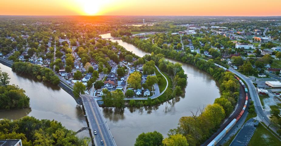 Image of Aerial horseshoe riverbend train and small cityscape landscape village sunrise neighborhood