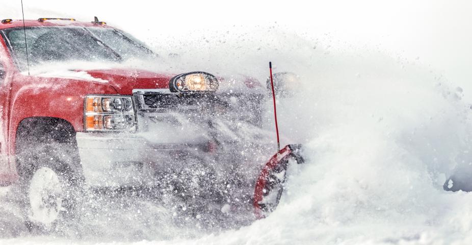 Fosston, USA - February 18, 2018: A red Chevrolet 4x4 pickup truck with a blade is plowing fresh powder snow after a winter snowstorm in northern Minnesota.