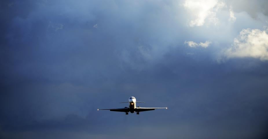Front view of sunlit airplane landing in bad weather