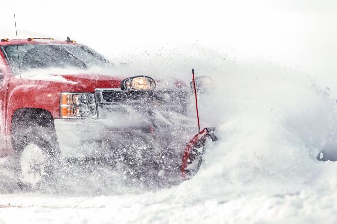 Fosston, USA - February 18, 2018: A red Chevrolet 4x4 pickup truck with a blade is plowing fresh powder snow after a winter snowstorm in northern Minnesota.