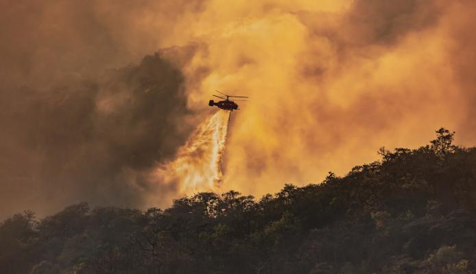 Helicopter doing a water drop on a wildfire