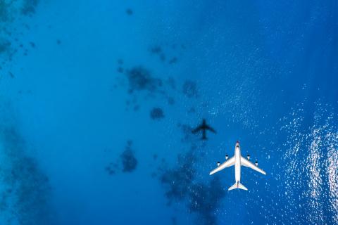 Aerial top down view of an airplane flying over blue sea