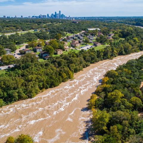 Austin Flooding aerial drone view from high above Colorado River and Red Bud Isle Flood waters with Austin , Texas skyline in the far distance