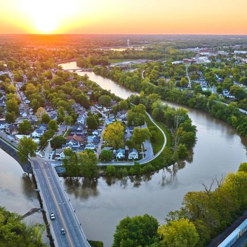 Image of Aerial horseshoe riverbend train and small cityscape landscape village sunrise neighborhood