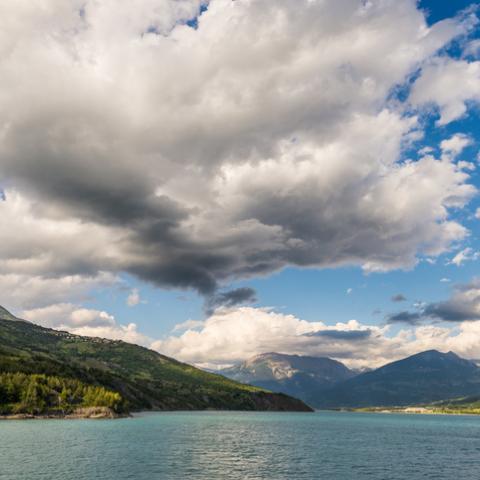 Blue lake amid mountain range and dramatic sky in idyllic uncontaminated environment once covered by glaciers.