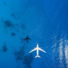 Aerial top down view of an airplane flying over blue sea
