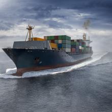 Aerial view of a big cargo container ship traveling over the ocean with fog and clouds