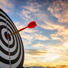 Benefits assessment. Red dart arrow hitting in the target center of dartboard Target hit in the center.