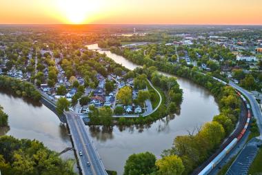 Image of Aerial horseshoe riverbend train and small cityscape landscape village sunrise neighborhood